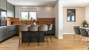 Une cuisine moderne dotée d’un îlot central, de meubles de couleur gris foncé et d’un mur d’accent en bois.