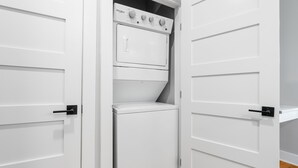 Ein Waschraum mit einer Whirlpool Waschmaschine und einem Trockner, weißen Türen und einem Holzboden.
