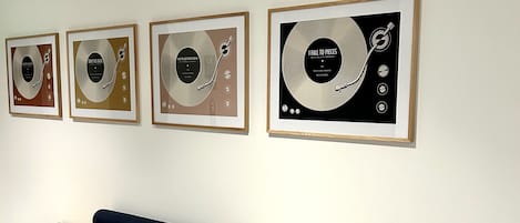 Un espace d’accueil avec un banc en bois et des pochettes de disques vinyles encadrées accrochées au mur.