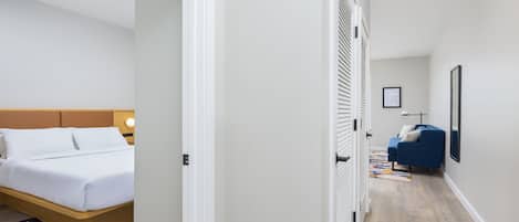 A hotel room with a bed, a bedside table, a nightstand, and a window with blinds.