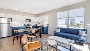 A modern kitchen with white cabinets, a stainless steel refrigerator, and a dining area with a table and chairs. - Motif on Nashville's Music Row (Nashville)