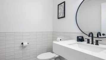 Un baño moderno con inodoro, lavabo y espejo.