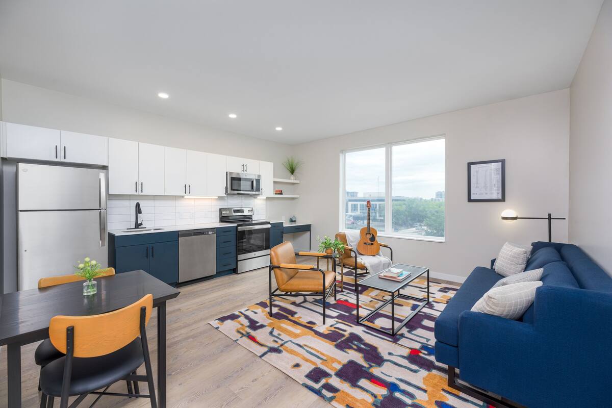 A modern apartment with a kitchen, dining area, and living room.
