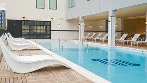 A modern hotel pool area with a long, straight pool, lounge chairs, and a covered seating area. - Motif on Nashville's Music Row (Nashville)