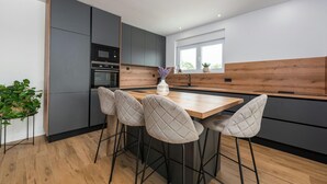 Eine moderne Küche mit einer Holztheke, Barhocker und integrierten Geräten.