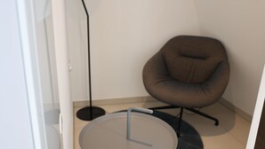 Ein modernes Zimmer mit einem runden Tisch, einem braunen Stuhl und einer Stehlampe.