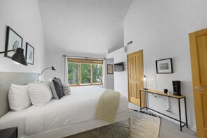 Un dormitorio con una cama, una mesita de noche con lámpara, un televisor y una puerta de madera.