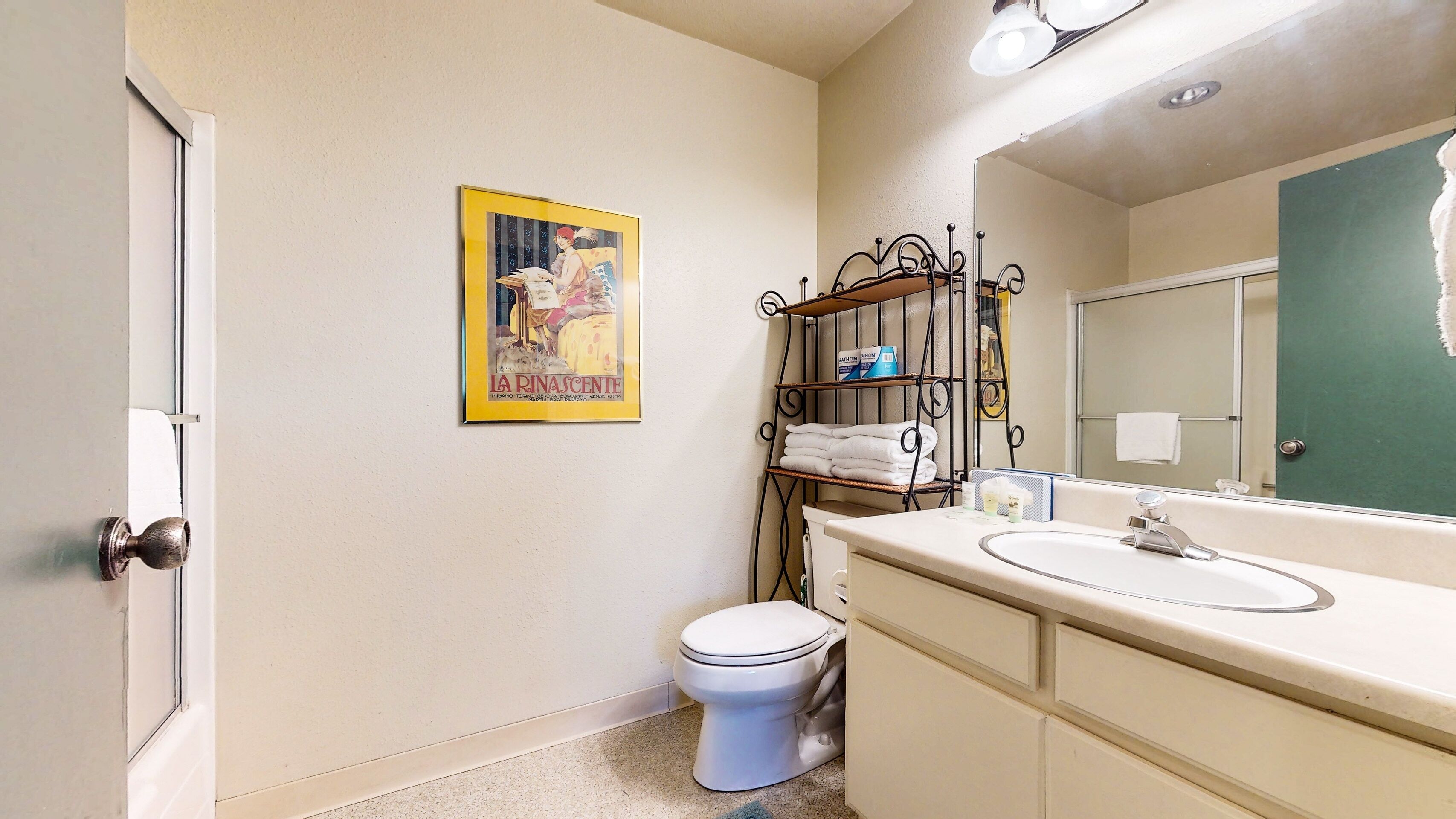 A bathroom with a toilet, sink, and a shelf with towels.