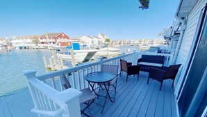 Um terraço com mesa e cadeiras, com vista para uma marina com barcos e casas.