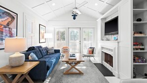 Un salon moderne avec un canapé bleu, une table basse en bois, une cheminée et un téléviseur fixé au mur.