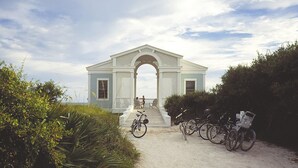 Un bâtiment doté d’un porche blanc et d’une arche, entouré de verdure.