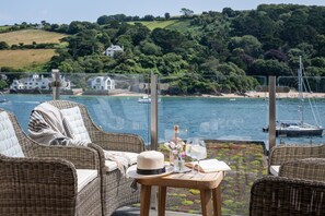 Relax in a serene outdoor space with a chair and table, overlooking a tranquil body of water and scenic surroundings.