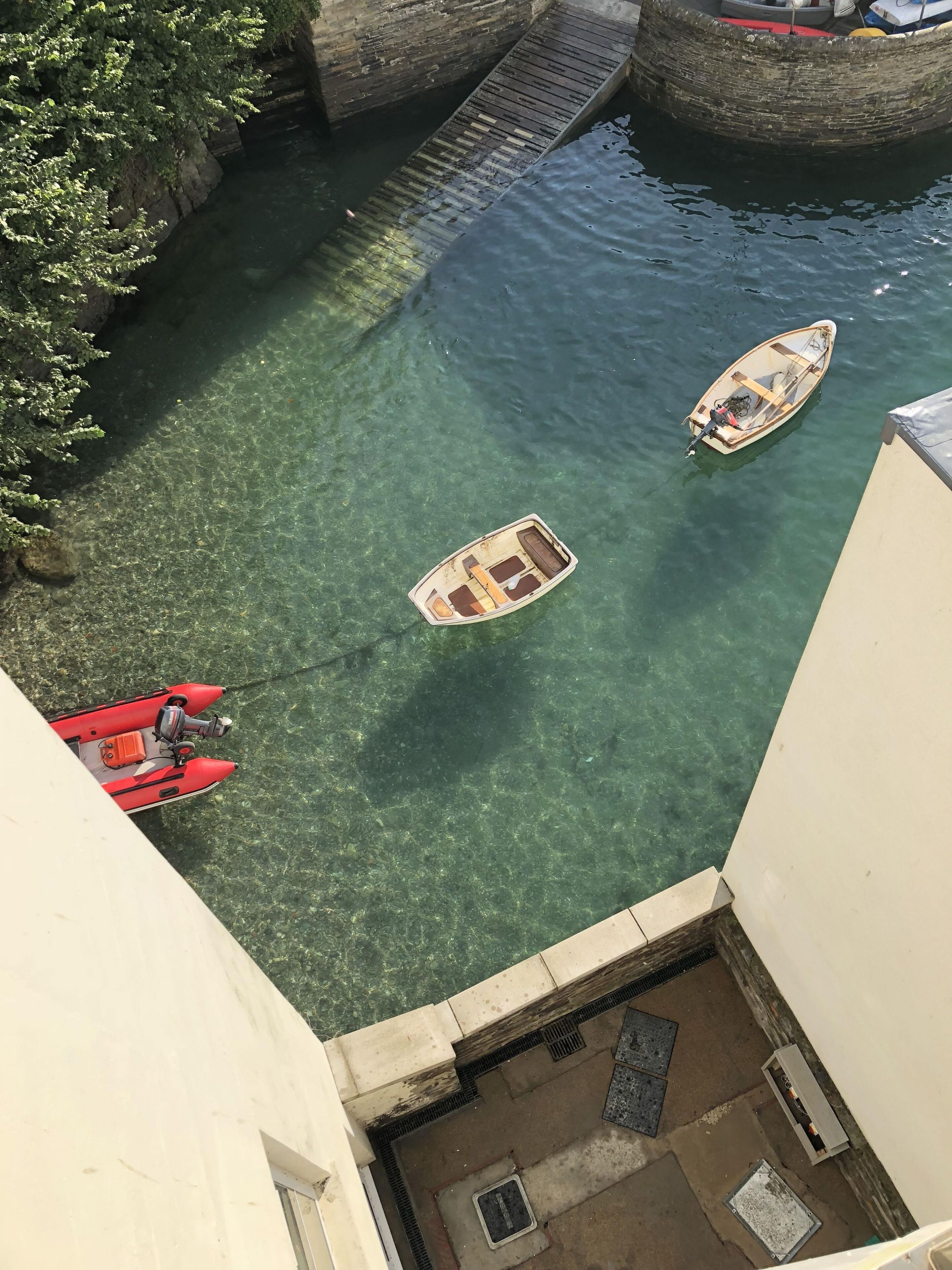 A narrow waterway with two boats and a red motorboat docked on the left.