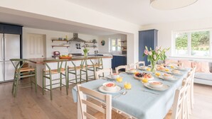 Una cocina moderna con comedor, que presenta una mesa larga preparada para el desayuno, con diversos platos y bebidas.