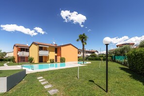Un immeuble résidentiel doté d’une piscine, d’une pelouse bien entretenue et surplombant un ciel bleu dégagé.