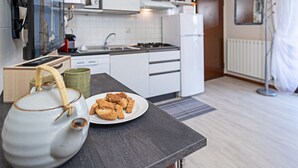 Een moderne keuken met witte kastjes, een magnetron en een fornuis. Op het aanrecht staat een bord koekjes.