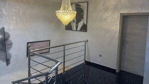 A modern interior with a marble staircase, a chandelier, and a framed artwork on the wall. - Lovely nb 3-bed House in Opebi (Lagos)