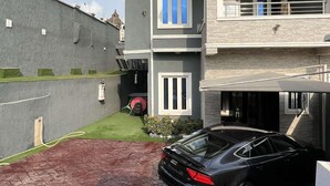 A modern two-story house with a car parked in the driveway. - Lovely nb 3-bed House in Opebi (Lagos)