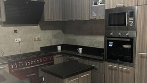 A modern kitchen with a central island, built-in microwave, oven, and stove. - Lovely nb 3-bed House in Opebi (Lagos)