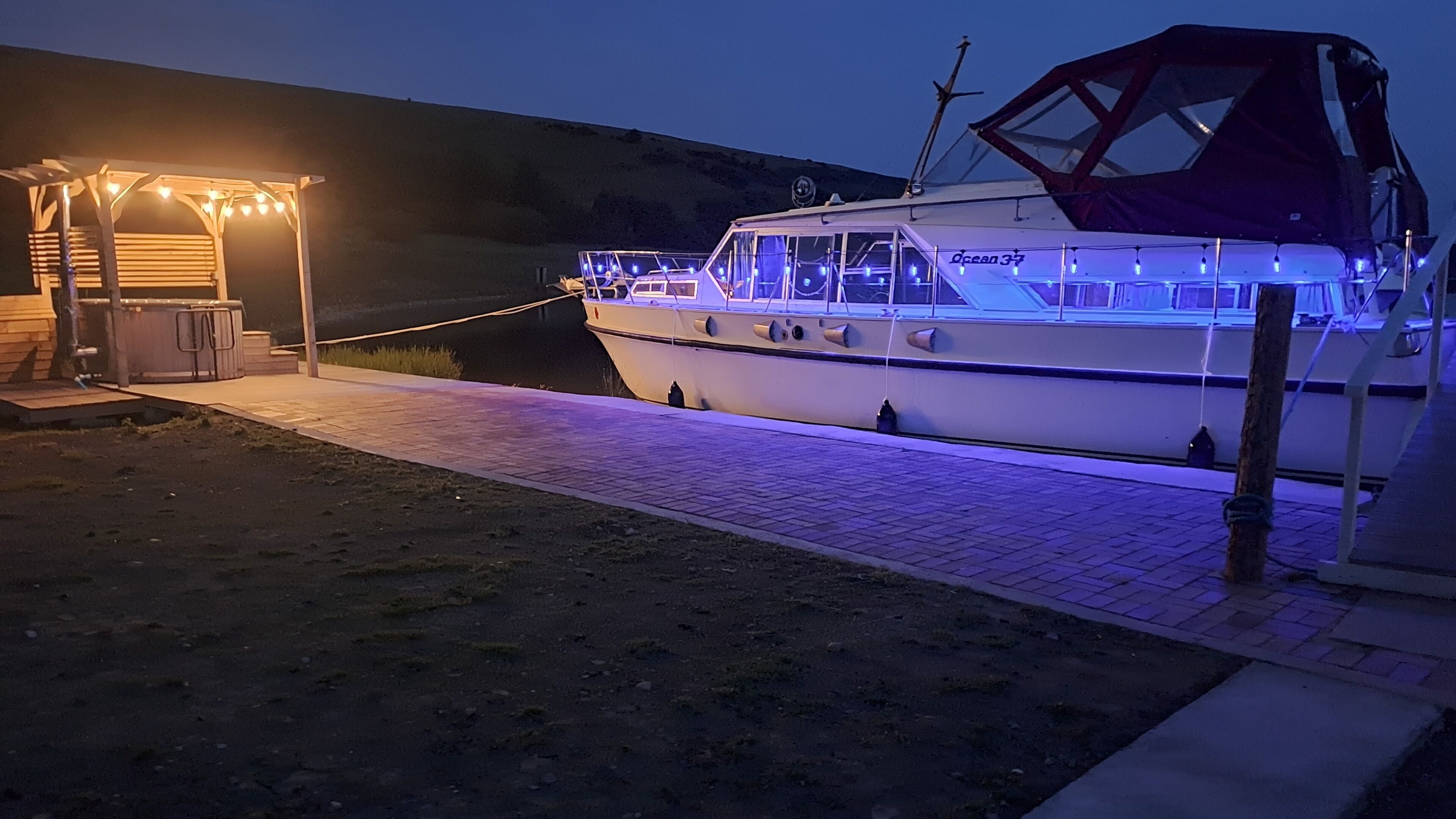 Un bateau était amarré dans une marina, avec une passerelle couverte et un bâtiment sur lequel on pouvait lire l’inscription « Ocean 37 ».