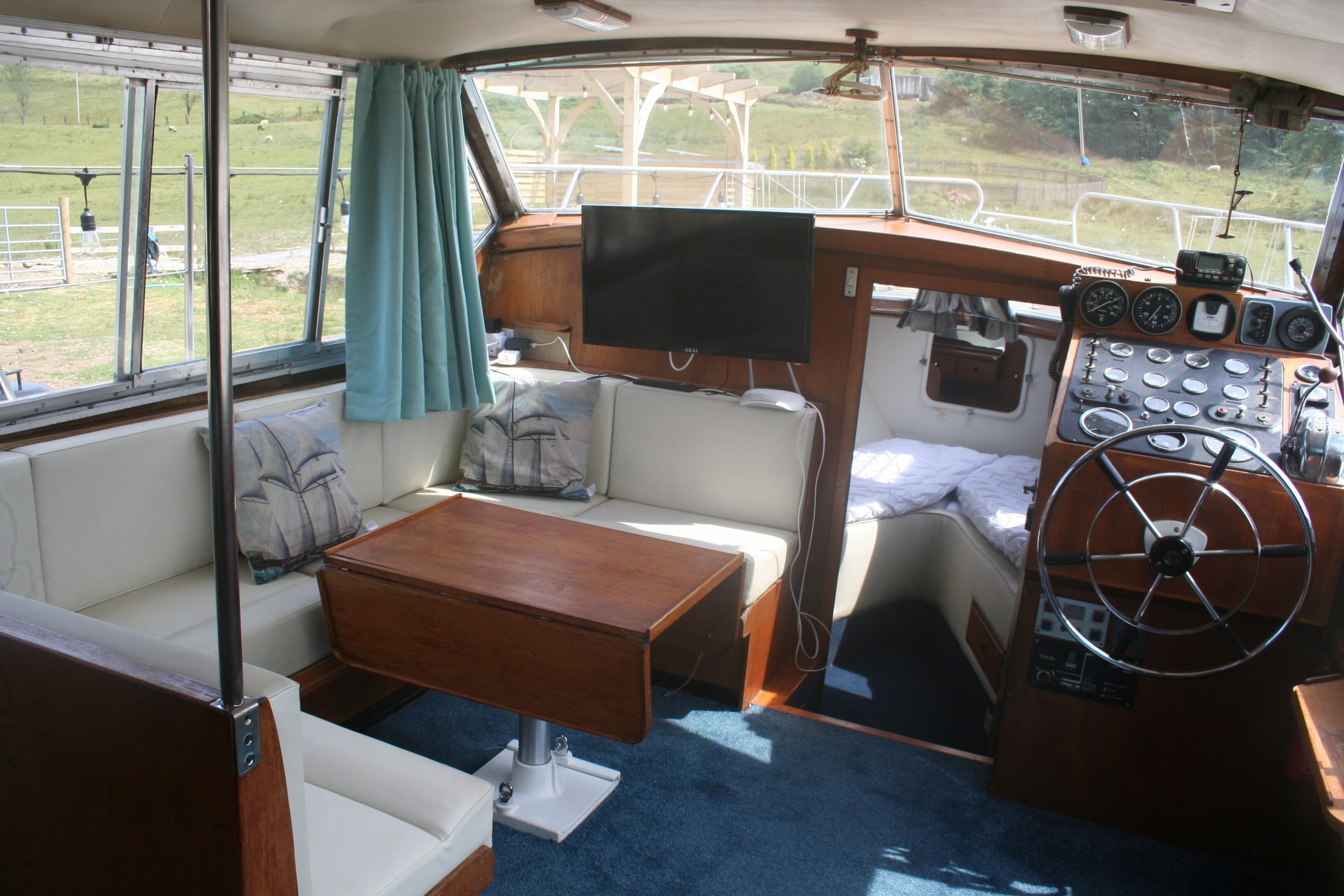 Interior de un barco con una zona de estar confortable, un panel de control y un televisor.