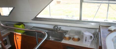 A compact kitchen with a sink, a coffee maker, and a window offering a view of the outdoors.