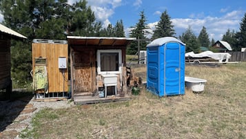 A small wooden cabin with a bathroom and a blue portable toilet.