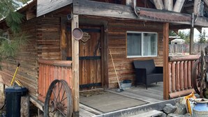 A rustic cabin with a wooden exterior, a porch, and a large wheel. - Beautiful cabin with rustic charm in Eureka, MT! (Eureka)