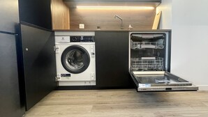 Eine kompakte Küche mit integrierter Waschmaschine und Trockner, Holzschränken und modernem Design.