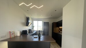 Eine moderne Küche mit einer zentralen Kochinsel, integrierten Geräten und einem großen Fenster für natürliches Licht.