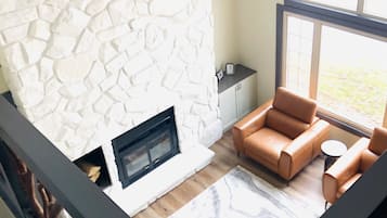 Un salon moderne avec une cheminée en pierre, des canapés en cuir et de grandes fenêtres.