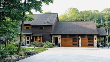 A modern two-story house with a stone facade, a large garage with wooden doors, and a well-maintained front yard.