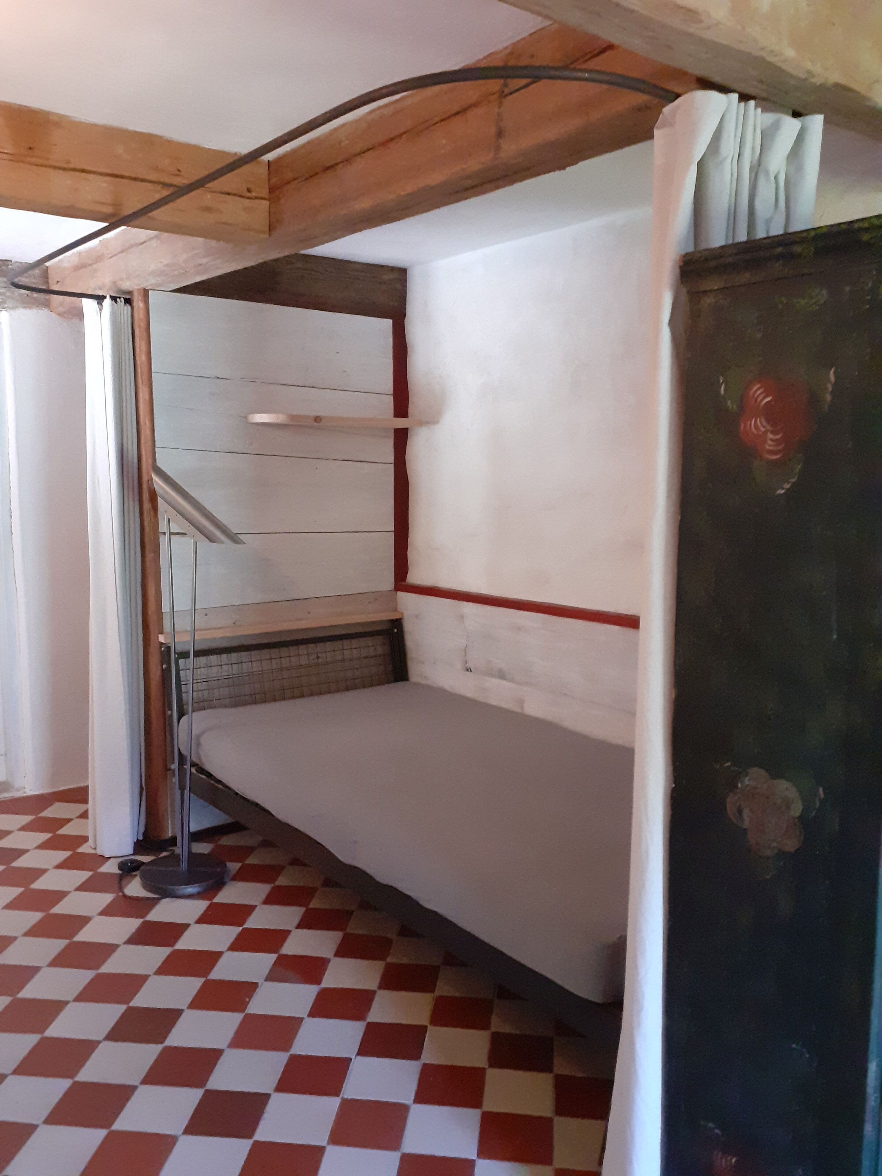 Une pièce avec un lit superposé, une échelle en métal, un sol à carreaux et un plafond en bois.