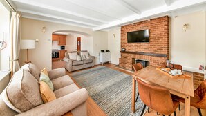 Un salon avec une cheminée, un coin repas et une cuisine à l’arrière-plan.