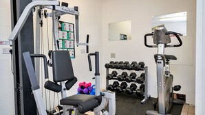 A gym with exercise equipment, dumbbells, and a mirror.