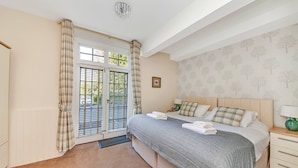 A bedroom with a bed, bedside table, and a window with curtains.