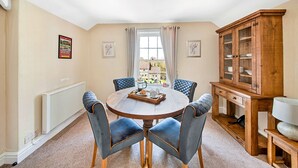 A dining area with a round table, four chairs, a cabinet, and a radiator. - Pennine Hall Apt (Thirsk)