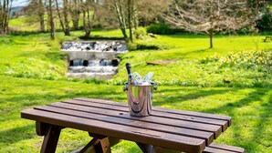 A picnic table with a metal container holding a bottle and glasses. - Ryedale Hall Cottage (Thirsk)
