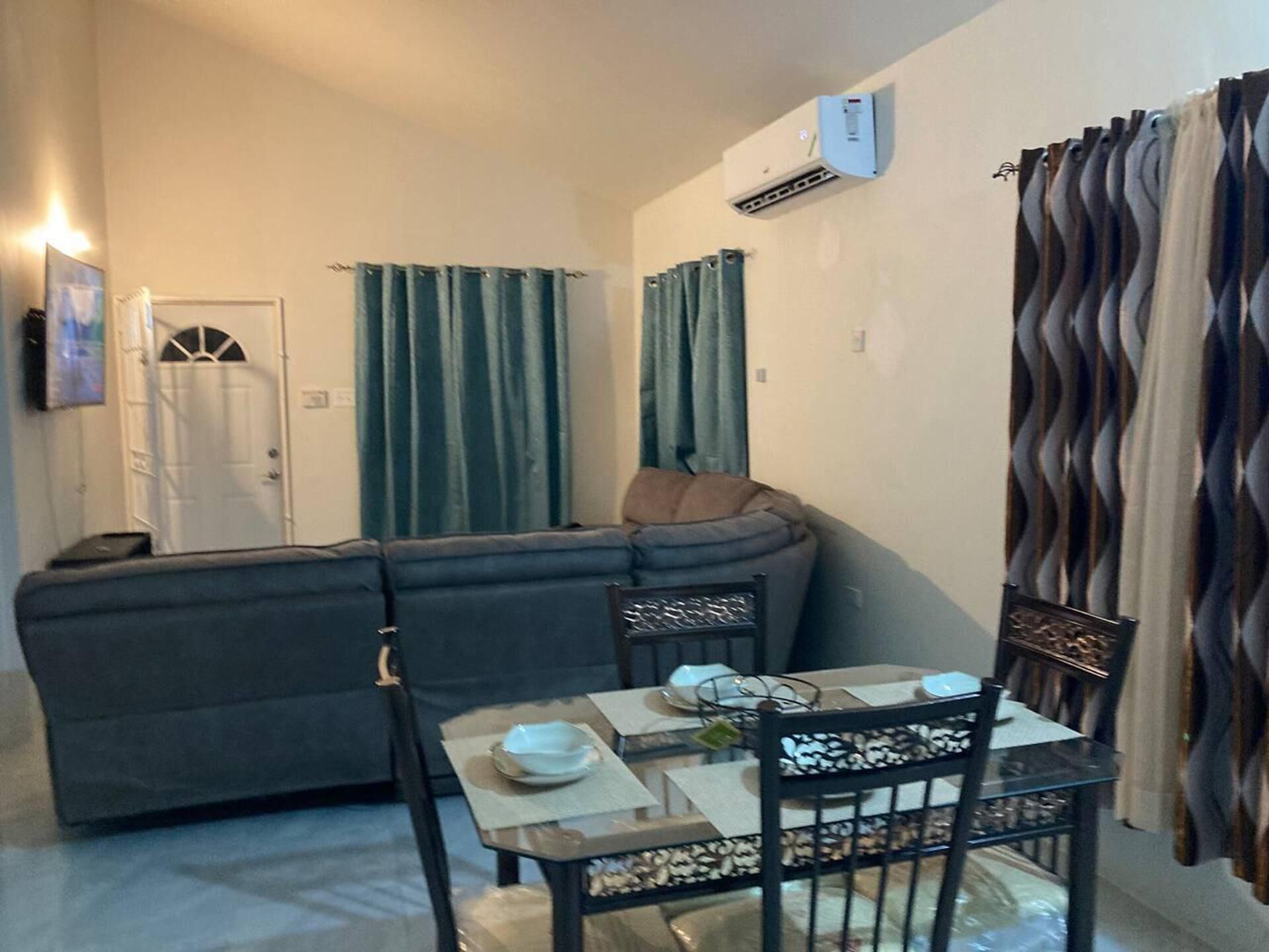 A compact living space with a sofa, a dining table with chairs, and a small kitchen area.