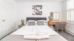 A bedroom with a bed, a desk, a chair, a mirror, and a window with blinds. - 7 Longfield Terrace · Gorgeous Central 5 Bed House in York with Parking - Pass The Keys (York)