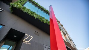 Un bâtiment moderne doté d’une façade en verre, d’un élément vertical rouge et du chiffre 27.