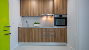 Une cuisine moderne avec des meubles en bois, un four en acier inoxydable et un mur d’accent d’un vert vif.