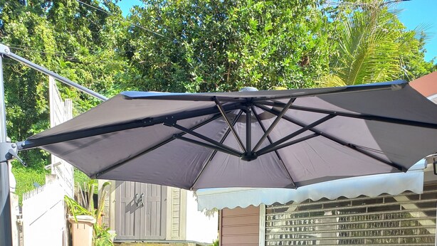 An outdoor patio with wicker furniture, a barbecue grill, and a large umbrella.