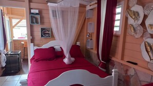 A bed with a white frame and red bedding, a white canopy, and a wall with decorative fish and shells.