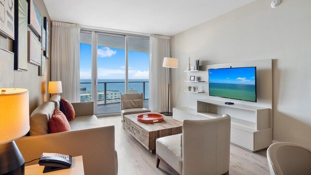 Ein modernes Hotelzimmer mit großem Balkon, Flachbildfernseher und minimalistischer Einrichtung.