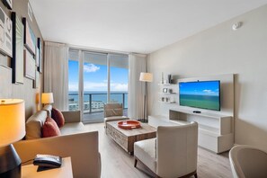 Una habitación de hotel moderna con un balcón grande, televisión de pantalla plana y una decoración minimalista.