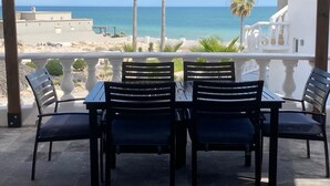Una terrazza con tavolo e sedie che si affaccia su una spiaggia.