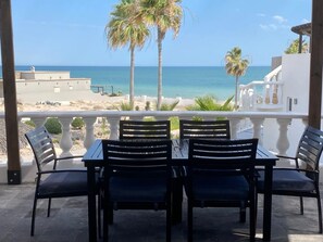 Een terras met een tafel en stoelen met uitzicht op een strand.