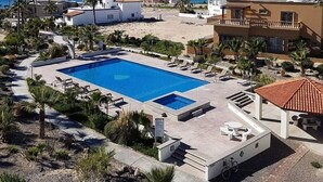 Un resort con una grande piscina, palme e vista sul mare.