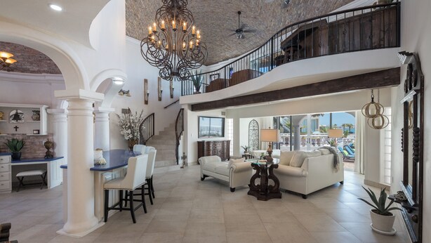 Un'ampia zona giorno con soffitto alto, un lampadario e una scala che conduce a un piano superiore.